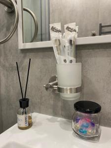 a bathroom sink with a jar of toothbrushes at Contento Apartments in Almaty
