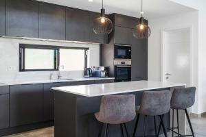 Villa Tapya - Amazing Villa with private pool في كاب مالهيريوكْسْ: مطبخ مع دواليب سوداء ومكتب مع كراسي بار