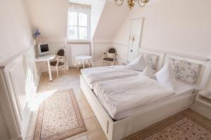 a white bedroom with a bed and a desk at Hotel Fürstenberger Hof in Xanten