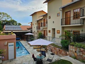 an outdoor patio with an umbrella and a swimming pool at Pousada Mãe Natureza in Pirenópolis