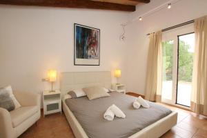 a bedroom with a bed with a chair and a window at Son Cami in S'Horta +13 photos