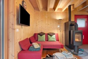 a living room with a red couch and a fireplace at Laugen Lodge in San Pancrazio dʼUltimo