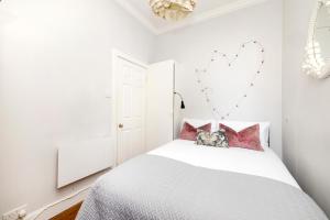 Habitación blanca con cama con almohadas rosas en JOIVY Classy Apartment near Edinburgh Castle, en Edimburgo