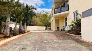 an empty driveway in front of a house with palm trees at Elegant 3 bedrooms of 3 Apartments in Rivière Noire