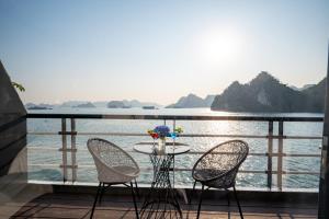 a table and chairs on a balcony overlooking the water at Dragon Premium Cruise Halong in Ha Long