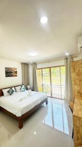 a bedroom with a large bed and a balcony at Jenny Garden House in Ban Madua Wan