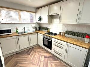 a kitchen with white cabinets and a wooden floor at Leamington Spa-3 Bed-Garden-Pets-Free Parking in Leamington Spa +20 photos