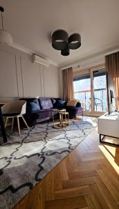 a living room with a purple couch and a rug at VipWarsawApartments Cytryn Mennica Residence in Warsaw