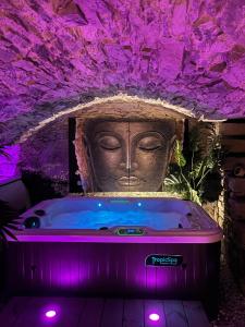 wanna z posągiem w pokoju z fioletowym oświetleniem w obiekcie La Voûte du Pilat & options SPA, massage w mieście Saint-Chamond