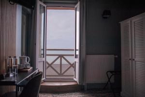 an open door to a balcony with a view of the ocean at l'itinerance in Mers-les-Bains