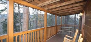 a porch of a cabin with two chairs and trees at Mountain Laurel in Sevierville +2 photos