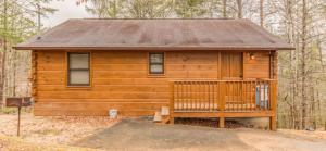 a wooden cabin with a porch in the woods at Mountain Laurel in Sevierville