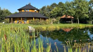 a house with a reflection in the water next to a lake at Agroturystyka Złoty Klon in Kijanka