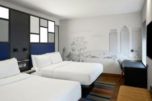 a hotel room with two beds and a desk at Aloft London Excel in London