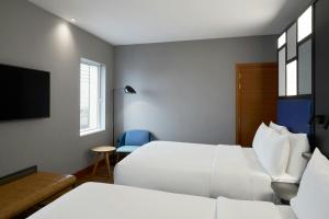 a hotel room with two beds and a tv at Aloft London Excel in London