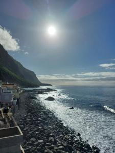 a rocky beach with the sun in the sky at Studio Casa Tropicana in Paul do Mar