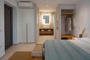 a bedroom with a bed and a bathroom with a sink at Kechria Bay Villas in Skiathos