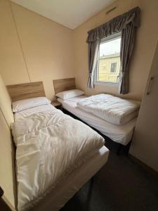 two beds in a small room with a window at Jay 28, California Cliffs, Parkdean, Sleeps Eight, Free Wi-Fi, Pet Friendly, Bed Linen and Towels Included in Great Yarmouth