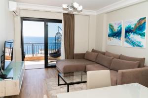 a living room with a couch and a view of the ocean at Blissful Apartments in Sarandë