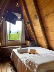 a bed in a wooden room with a window at Cabana com Vista para SERRA da Canastra in São Roque de Minas