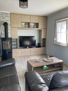 a living room with a couch and a tv at Villa à la campagne in Wanze