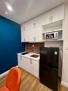 a kitchen with white cabinets and a black refrigerator at Hillside Luxury Apartments by CASEPIA in Phu Quoc
