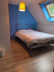 a bedroom with a bed with a blue wall and a window at Villa à la campagne in Wanze