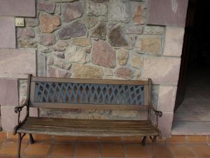 una panca di legno seduta di fronte a un muro di pietra di Posada El Cafetín a La Hermida