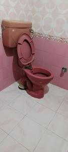 uma casa de banho com um WC vermelho numa parede cor-de-rosa em Hotel Hari Ganga - Harkipauri Road em Haridwār mais 15 fotografias