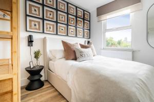 a bedroom with a white bed and framed pictures on the wall at Newly Designed, 2br Apt, 5min from Northwood London Tube Station, NATO HQ, Ideal for Wembley, Warner Studio, Contractors in Northwood