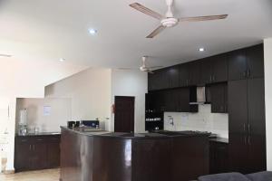 cocina con armarios marrones y ventilador de techo en Pearl House Villa Panayur ECR Beach, Chennai, en Chennai