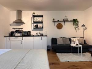 a living room with a black couch and a kitchen at BeimSchmied in Schechen