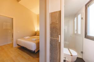 a small bedroom with a bed and a toilet at Bravissimo Calderers La Lleona, heart of the Barri Vell in Girona
