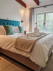 a large bed with a blue headboard in a bedroom at 37 Chakas Rock Chalets in Ballito +23 photos
