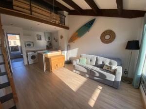 - un salon avec un canapé et une planche de surf sur le mur dans l'établissement Grand studio entre le golf et la plage à 800m, à Saint Cyprien Plage 7 autres photos
