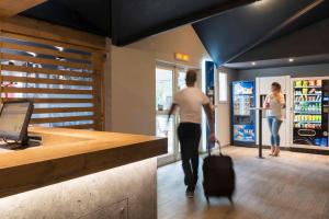 una persona con una maleta entrando en una tienda en Ibis Budget Béziers Est La Giniesse, en Béziers