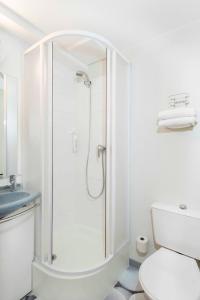 a white bathroom with a shower and a toilet at Ibis Budget Béziers Est La Giniesse in Béziers
