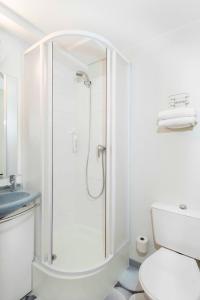 y baño blanco con ducha y aseo. en Ibis Budget Béziers Est La Giniesse, en Béziers