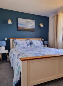 ein Schlafzimmer mit einem Bett mit einer blauen Wand in der Unterkunft Sandpiper Cottage: cosy home near the beach in Woolacombe
