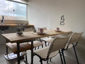 une table en bois avec quatre chaises et une table avec des tasses dessus dans l'établissement Apartamento Studio 203, à Juazeiro 23 autres photos