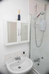 Un baño blanco con lavabo y ducha. en Emerald Excel City Airport o2 Apartment, en Londres 35 fotos más