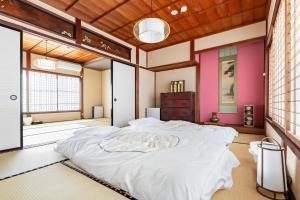 una camera da letto con un grande letto bianco di Manabi-stay Matsue 駅近伊勢宮町どこに行くにも最高に便利な古民家一棟貸切ホテル a Matsue
