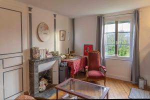 a living room with a table and a fireplace at Chambre d'Hôtes Les Jardins de Marie, SCI Charles III in Bernay