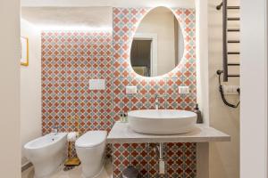 a bathroom with a sink and a toilet and a mirror at Rome As You Feel - Charming Space at Torre Argentina in Rome +10 photos