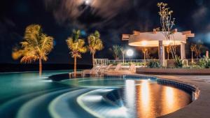 a swimming pool with palm trees and a building at Salinas Park Resort in Salinópolis