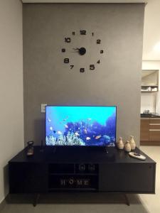 uma sala de estar com uma televisão de ecrã plano e um relógio em Residencial Verônica 06 - Apartamento de 1 quarto próximo ao centro em Marília
