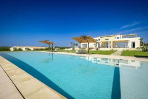 a large swimming pool in front of a house at Shalamu Luxury Apartments in Rosolini