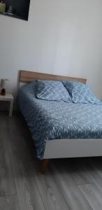 a bed with a blue comforter in a bedroom at Chambre indépendante avec frigo et micro-ondes in Poitiers