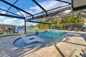 a swimming pool with two white chairs in the middle at Neptunes Villa-Canalfront, Heated Pool, Outdoor Kitchen, Tiki Hut in Cape Coral