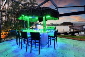 a bar with chairs and a table with a umbrella at Neptunes Villa-Canalfront, Heated Pool, Outdoor Kitchen, Tiki Hut in Cape Coral